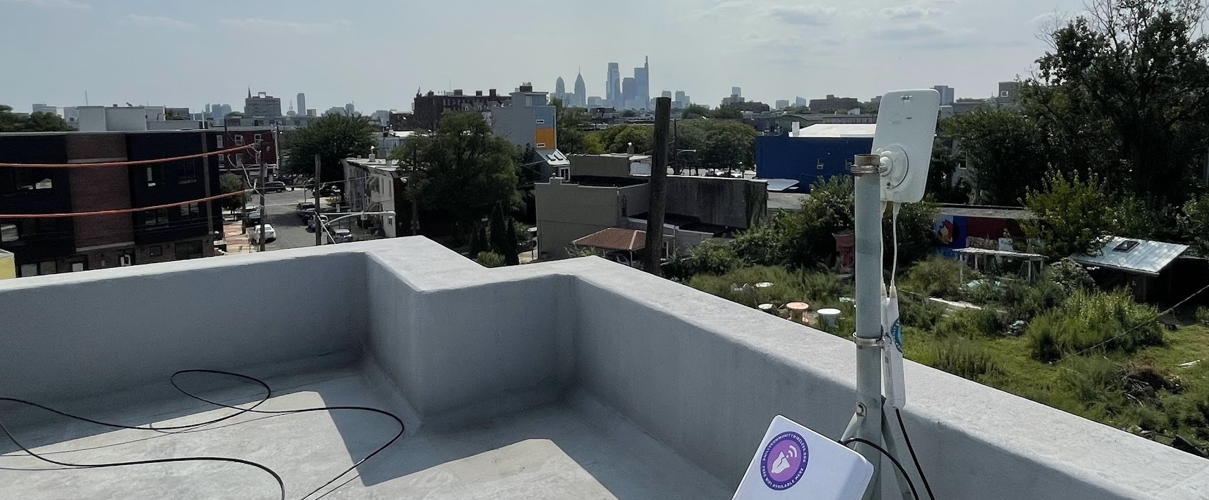 A photo of an antenna installed on a rooftop, pointing at a receiver tower in the distance.