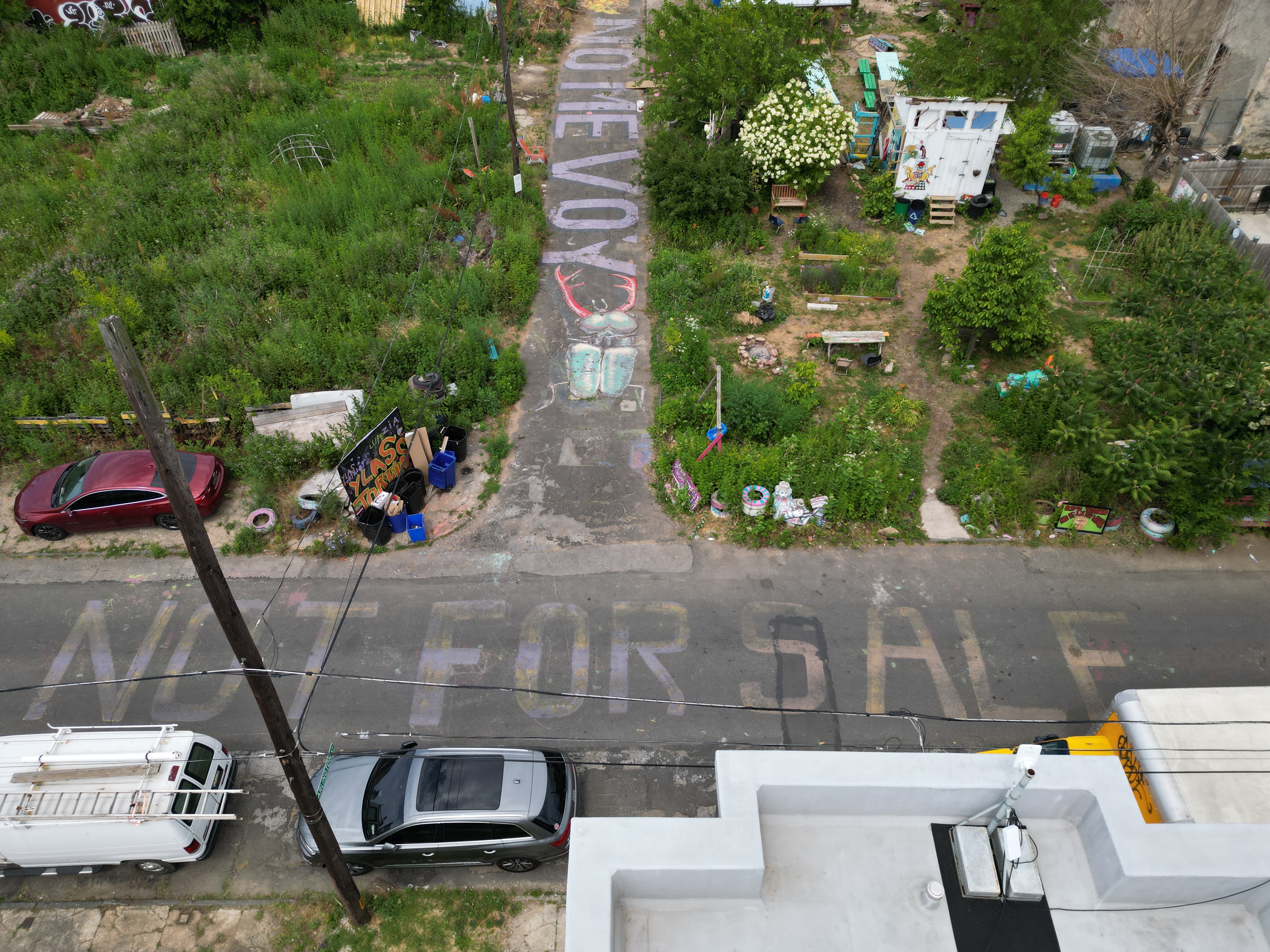 Drone photography of wireless antennas broadcasting wifi from residential rowhome into Cesar Andreu Iglesias Gardens, with writing visible on the street saying Not For Sale and No Me Voy