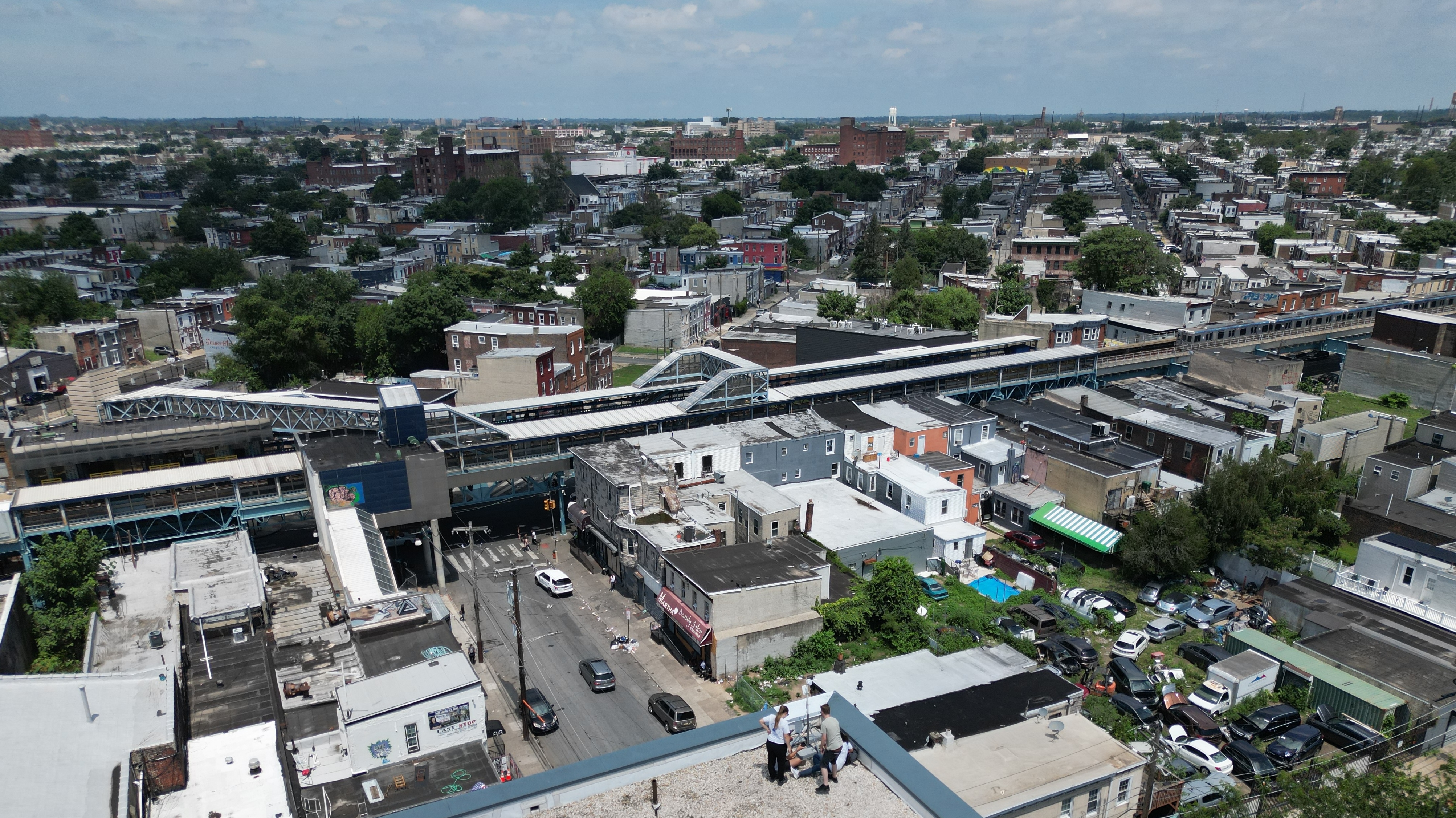 Birds-eye image of three people setting up equipment on a building roof, with the neighborhood in the background.