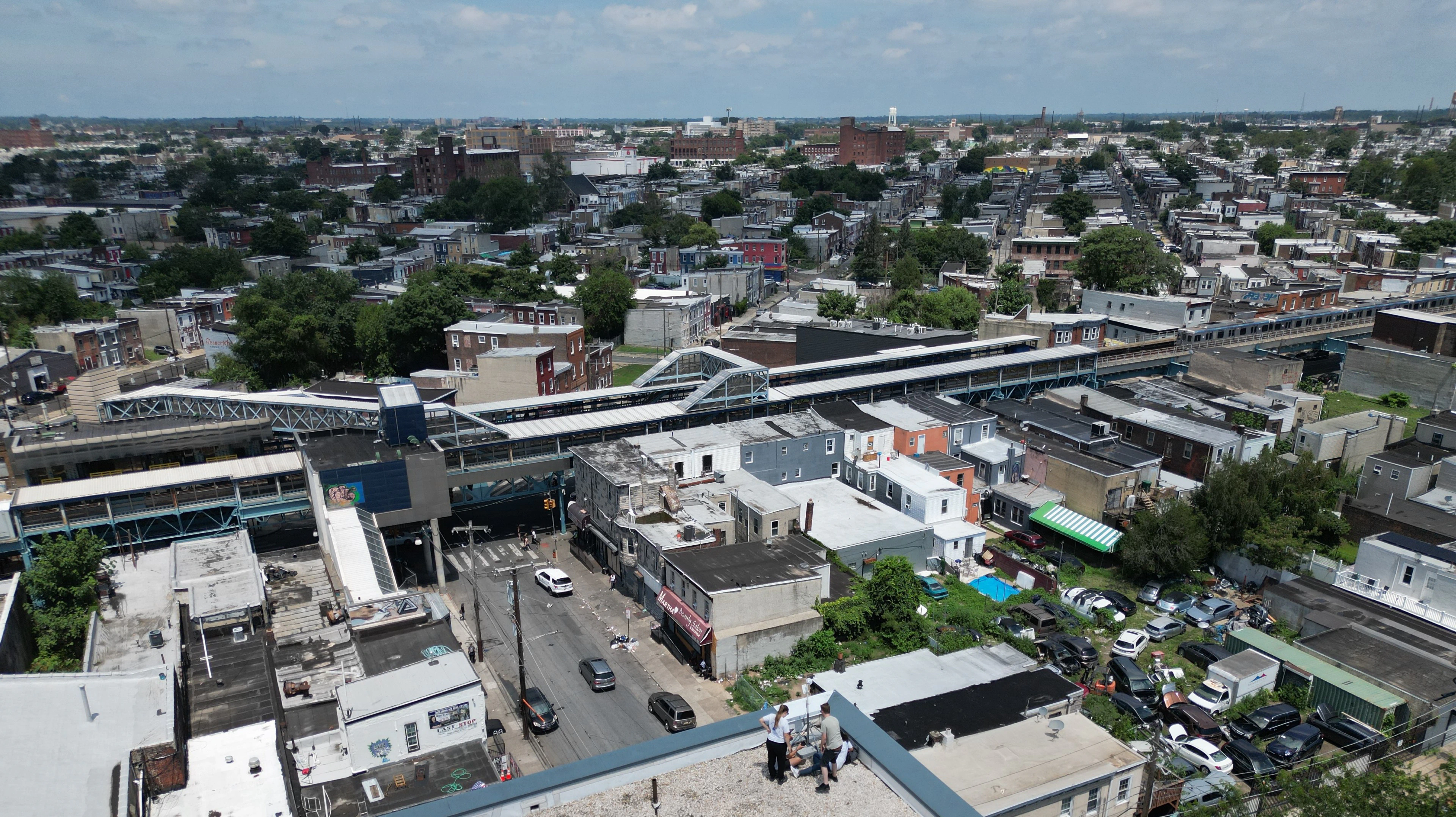 Birds-eye image of three people setting up equipment on a building roof, with the neighborhood in the background.