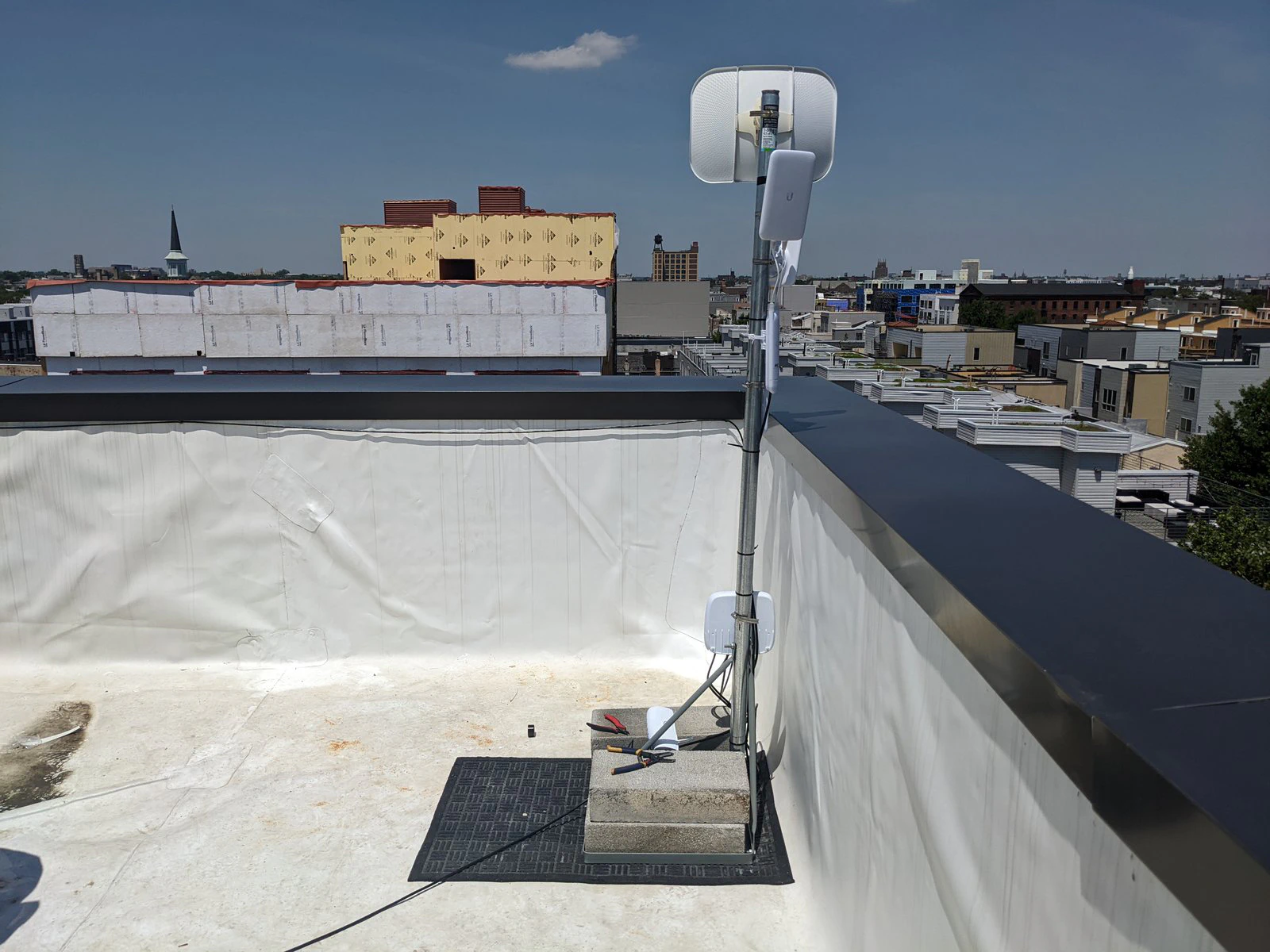 Una antena inalámbrica en un mástil al borde del techo de The Clay Studio, con vista a los techos de Filadelfia.