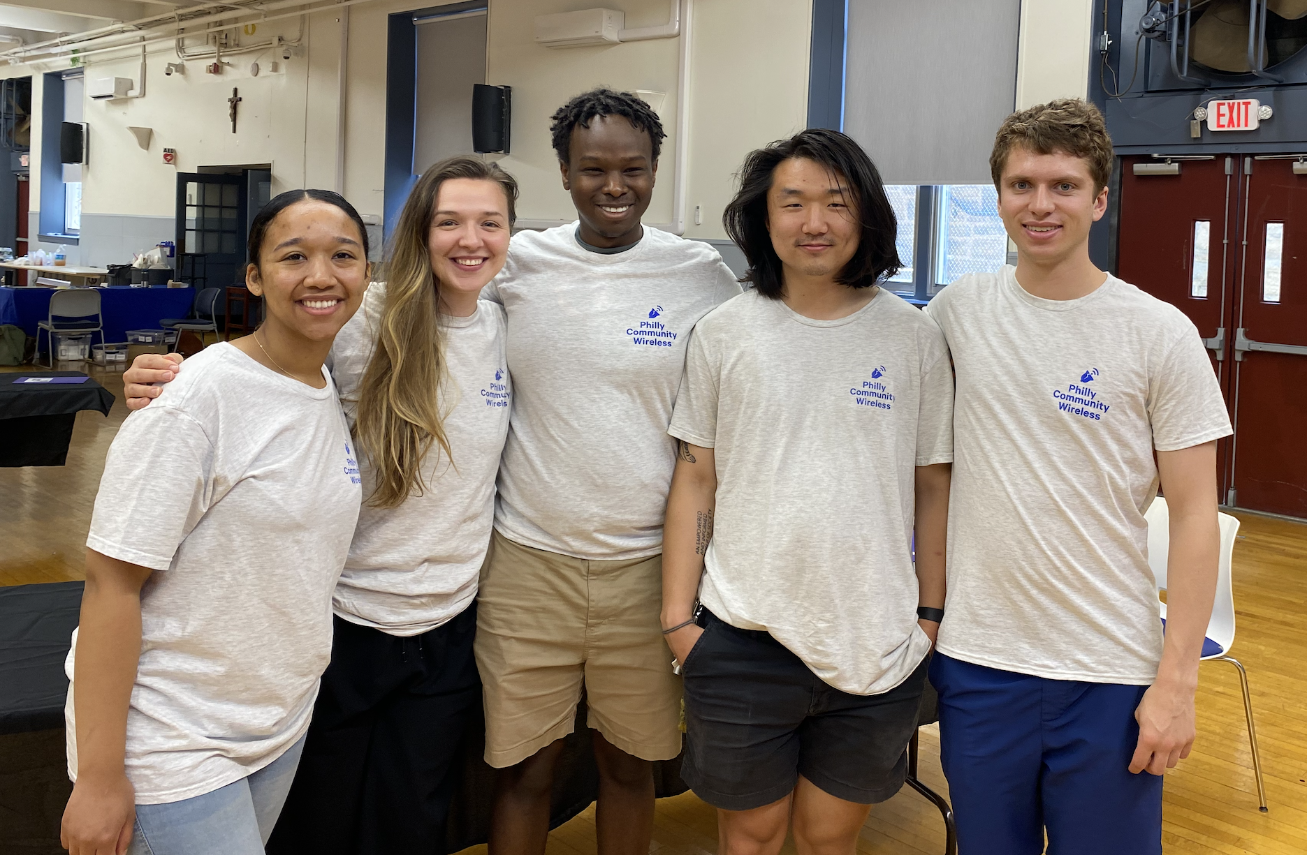 5 smiling people posing for a photo in matching PCW t-shirts.