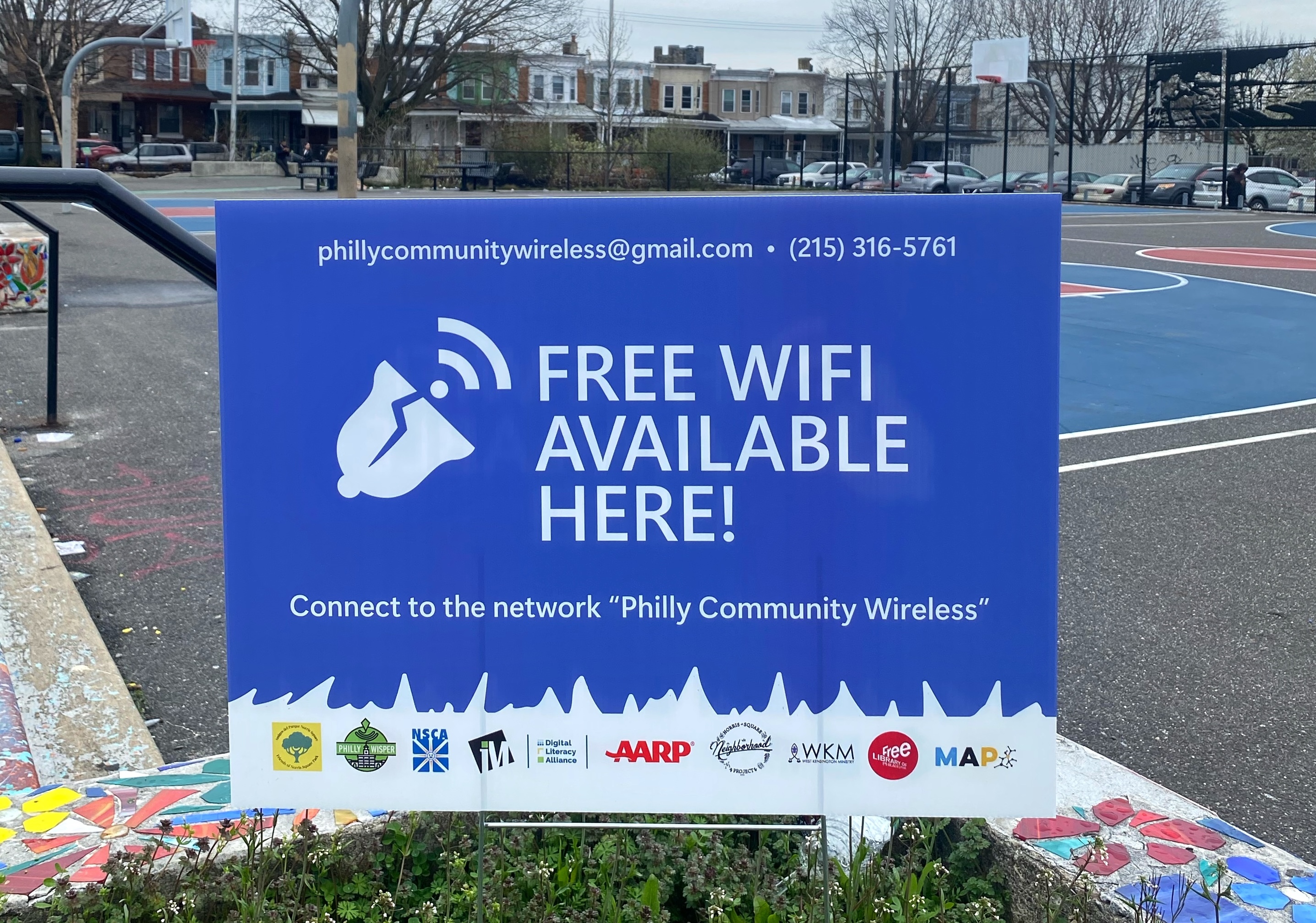 A PCW sign saying Free Wifi Available Here with PCW's contact information and logos of partner organizations.